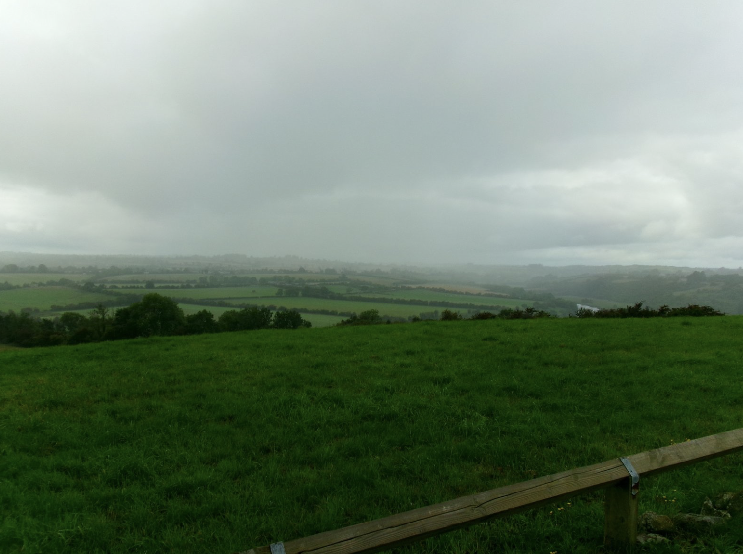 Green countryside rolling out under a moody sky