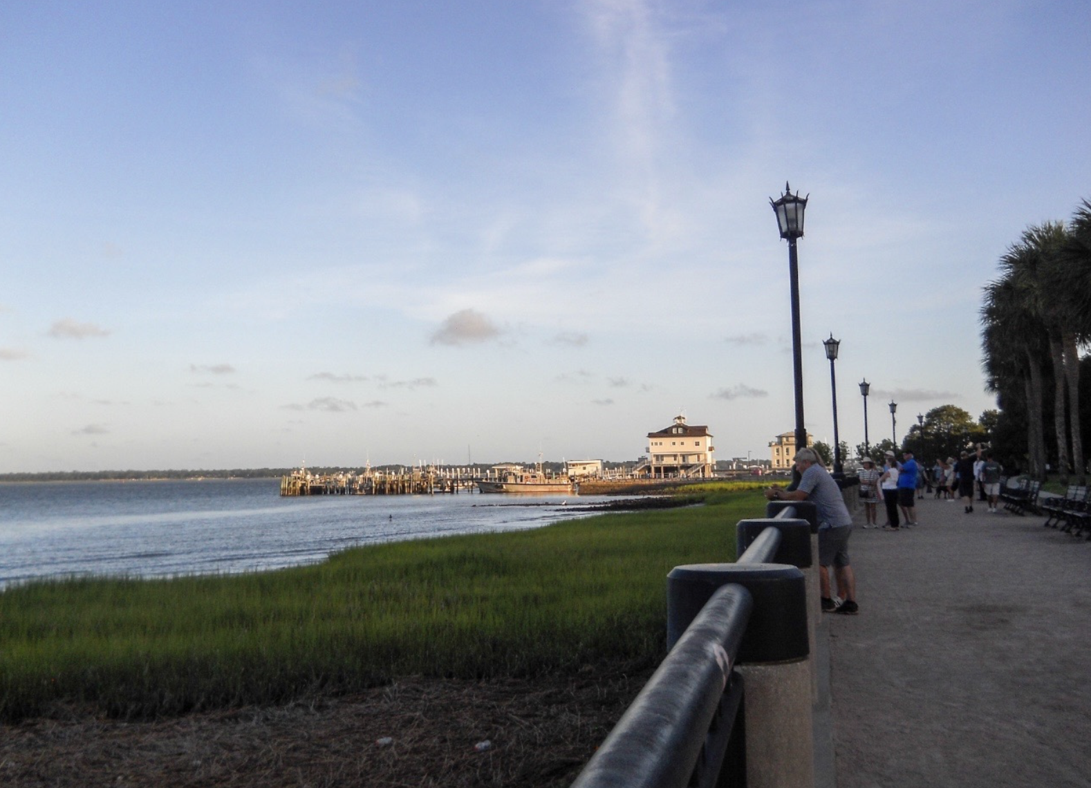 Waterfront promenade with marsh grass, lampposts and a distant pier