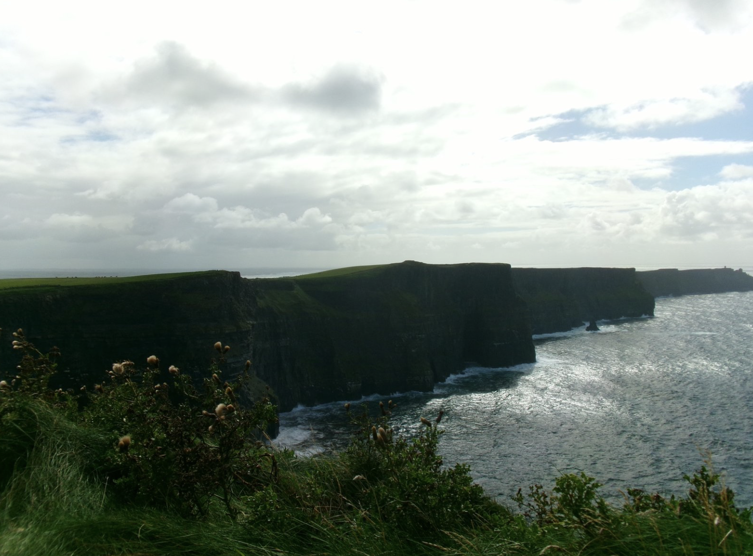 The Cliffs of Moher stretching into the sea beneath a cloudy sky